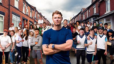 Freddie Flintoff stood at the front of a crowd of young cricket players in a residential red bricked street
