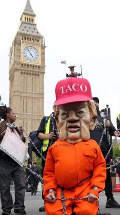 A person dressed as Donald Trump wears orange prison overalls and a red hat that says 'taco' in front of the Big Ben in London