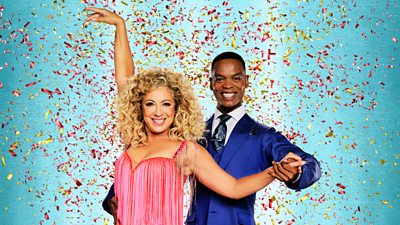 Alex Kingston wears a pink fringe trimmed dress and Johannes Radebe wears a blue suit and tie as they pose together