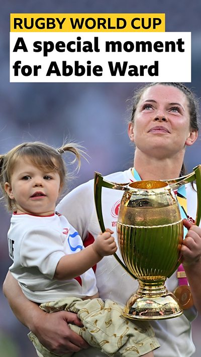 Abbie Ward carrying the World Cup Trophy and her young daughter, Hallie