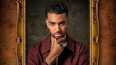A man with dark hair, a beard and moustache stares straight to camera stroking his chin in a portrait within a gold frame.