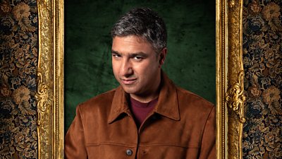 A man in a brown jacket and red t-shirt looks to camera with an eyebrow raised. His image is featured in a gold frame on a wall.