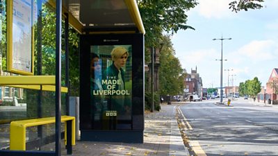 Made in Liverpool artwork on the inside of a yellow bus shelter on a street in Liverpool. The street has no people or cars passing.