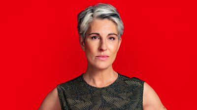 Close-up of Tamsin Greig in character as Holly Gaskell in Riot Women. She wears a black vest top and stares directly to the camera. 