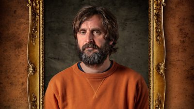 A man with a full beard and moustache looks to camera with an unimpressed face. He wears an orange jumper and his portrait is set within a gilded frame.