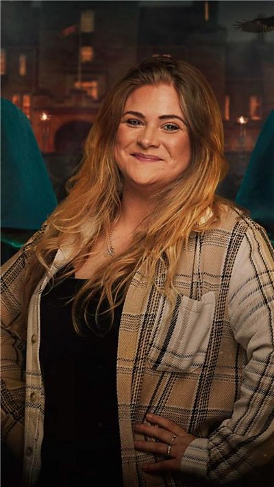 Charlie Bees stands with her hands on her hips.