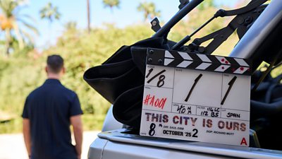 A clapperboard for filming on This City Is Ours series 2 rests on the back of a truck with filming visible in the background