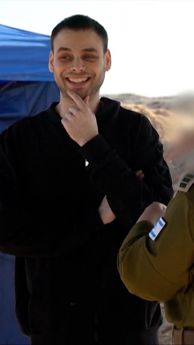 A freed hostage smiles while speaking to an Israeli soldier.