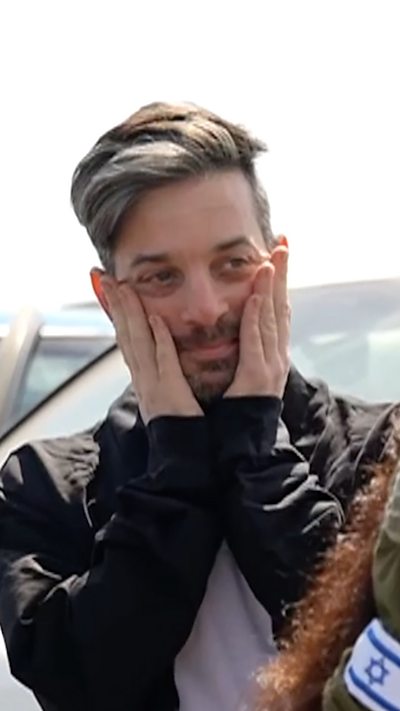 A freed Israeli hostage holds his face in his hands after being released from Hamas captivity.