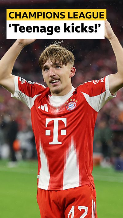 Lennart Karl celebrates with his arms in the air in red Bayern Munich kit
