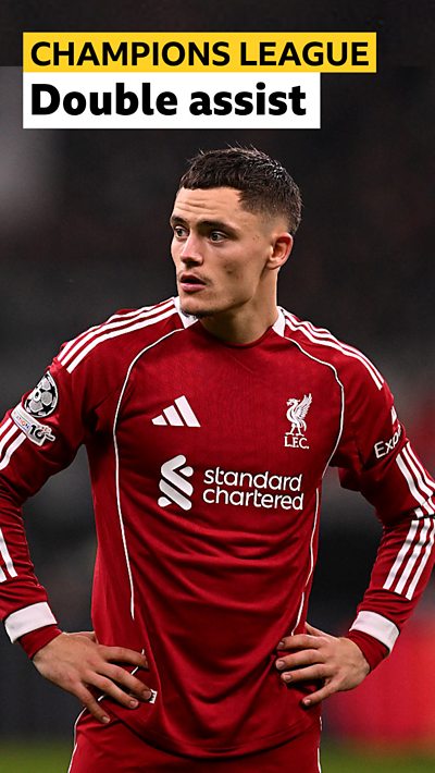 Florian Wirtz stands with hand on hips in red Liverpool home kit