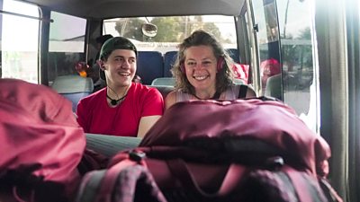 A man and a woman sit together on a bus smiling
