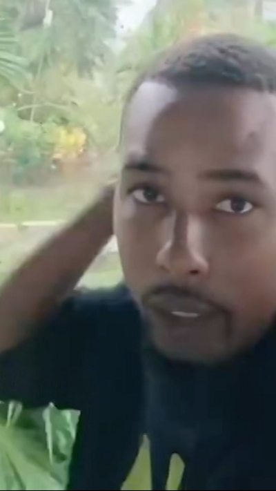 Shaquille Clarke holds on to his hood as winds blow in