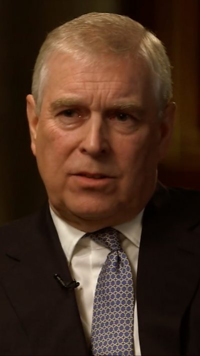 Andrew, who has grey hair, has a serious expression during the interview