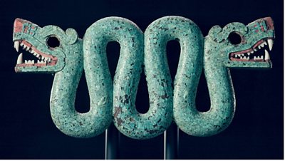 A sculpture of a double-headed serpent, embossed in green with mosaic style details