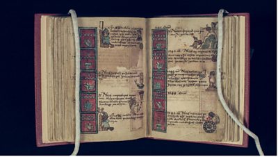 An open, ancient book with old text and colourful illustrations 