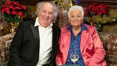 A man and woman sit on a sofa in the Queen Victoria pub smiling
