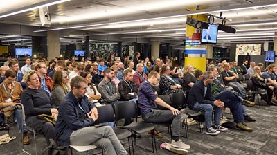 A selection of audience members listen to speakers in a conference hall setting