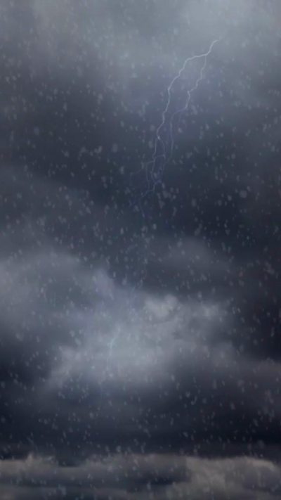 Lightning strikes through dark clouds and falling snow