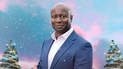 A man in a dark blue suit and light shirt smiles to camera, set against a backdrop of an animated snowy scene