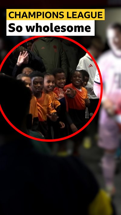 Young Arsenal fans waving towards Bukayo Saka