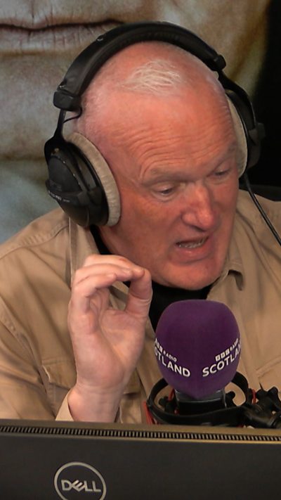 Kenny Macintyre with headphones on infront of a microphone
