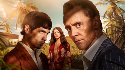 Two men and a woman are pictured against a tropical scene, with palm trees and lush green hills. One man in a suit stares to camera, looking serious whilst the other stares straight ahead at something off screen. The woman in the middle looks contemplative.