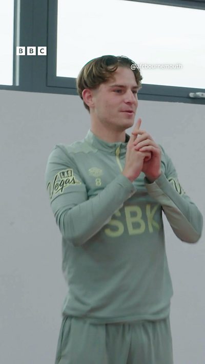 Keyframe #3 - Alex Scott standing up with his hands in front of him.