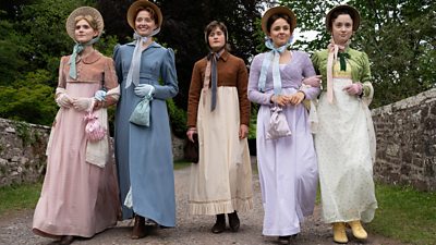 Five women walking across a bridge in the countryside. They all wear Regency-era clothing, including full-length dresses, bonnets, and small bags. Four of the women smile as they walk. One woman in the centre walks further behind and doesn’t look as cheerful. 
