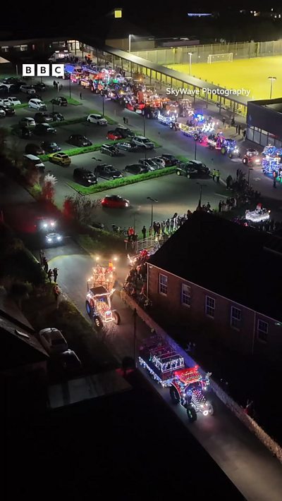 A drone shot showing tractors covered in fairy lights driving through Guernsey