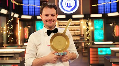 MasterChef Champion of Champions 2025 Thomas Frake holds a trophy in the shape of a golden frying pan. 