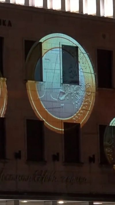 Projection on euro coin on facade of building
