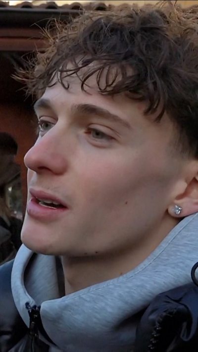Man with curly hair and grey jumper