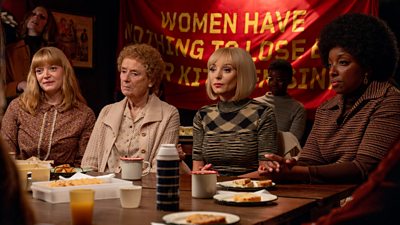 Rosalind Clifford (Natalie Quarry), Nurse Crane (Linda Bassett), Trixie Franklin (Helen George), Joyce Highland (Renee Bailey) during a scene for Call The Midwife. The four characters sit at a table with drinks and snacks. A banner hung in the background is partially obscured, but the text "Women have nothing to lose" is visible. 