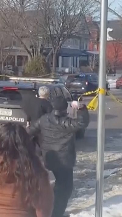 A protestor throws a snowball at a police vehicle.