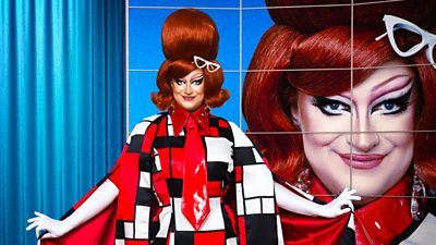 A drag queen (Kate Butch) poses in a black, red and white ensemble with a close-up of her face lit up behind her.