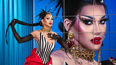 Minty Fresh, the drag queen, poses with a long plaited ponytail and a black and white striped corset with statement jewelry