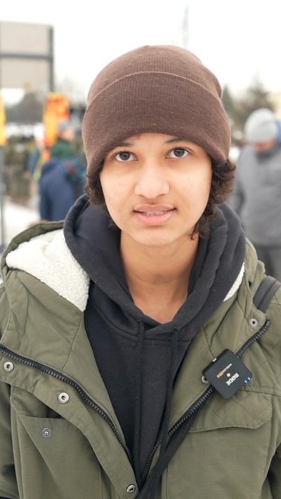 Young protester in green jacket looks into the camera.