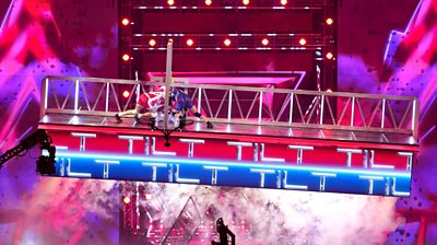 A screenshot from the show Gladiators: a Contender and a Gladiator battle against each other on a suspended platform
