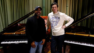 Vernon Kay and Darius stand together smiling between two pianos