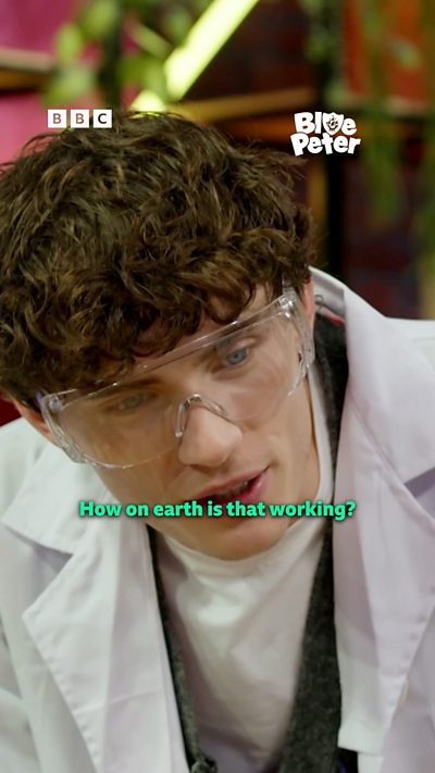 Joel in a lab coat and safety glasses watching a science experiment.