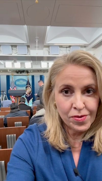 Sarah Smith, wearing blue, stands in the White House press room.