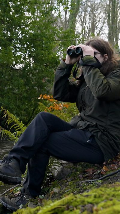 Naturalist Dara McAnulty looks through his binoculars sitting on the ground at Mount Stewart