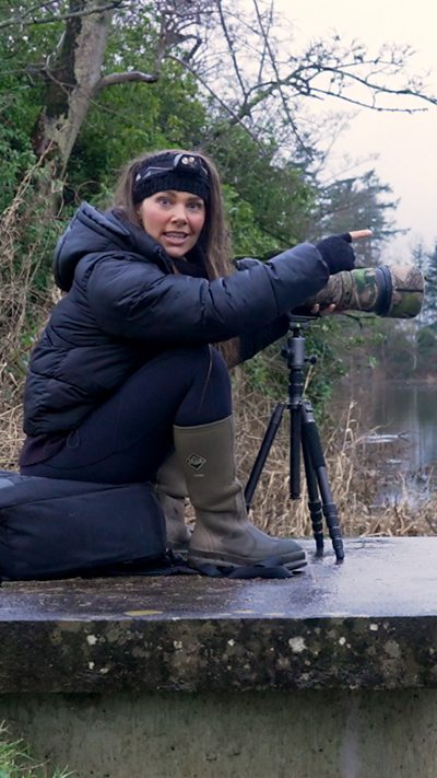Winterwatch presenter Hannah Stitfall points across a river