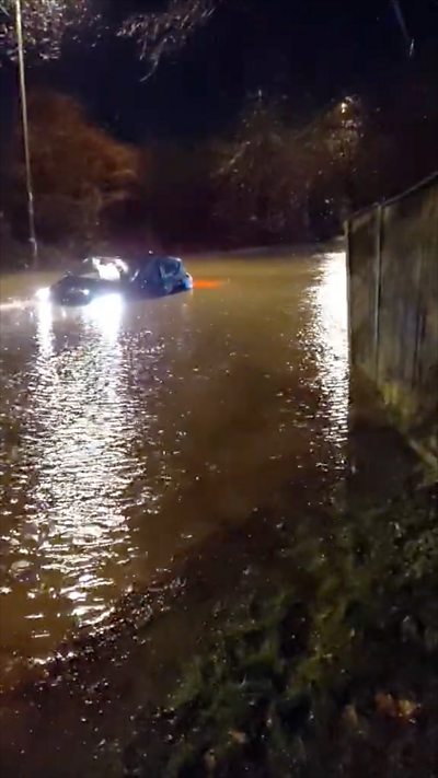 A car stuck in flood water in the dark.