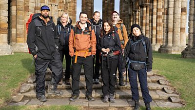 A group of celebrities, wearing hiking gear, pose for a photo celebrating series 8 of Pilgrimage 