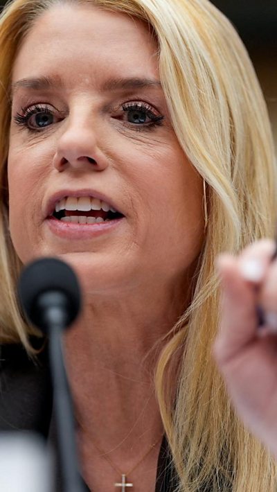 Pam Bondi speaks behind a microphone.