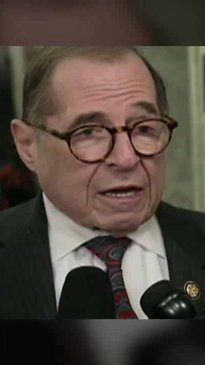 Representative Nadler wearing glasses and speaking into two microphones held in front of him.