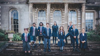 Children in school uniform stand on steps in front of pillars