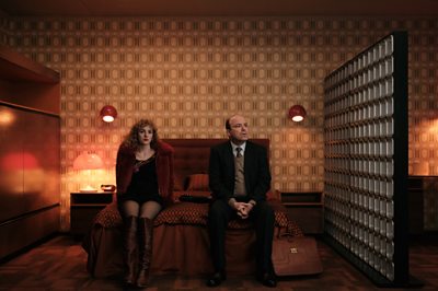 A man and a woman sit on a bed.